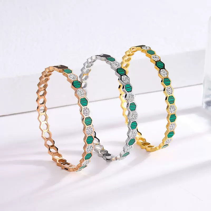 Three hexagonal patterned bracelets in gold, silver, and rose gold on a white background
