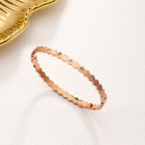 Rose gold bracelet with small diamonds on a white background