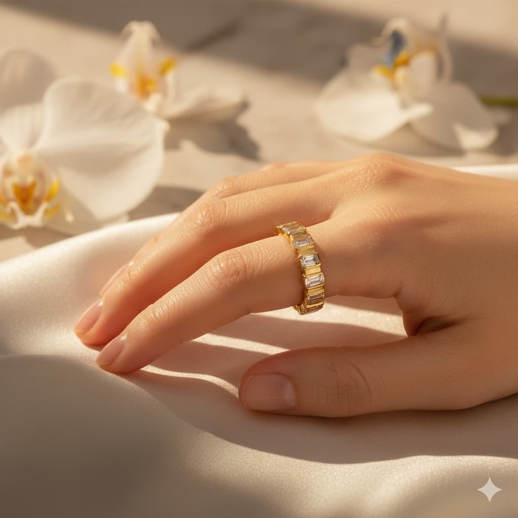 Hand wearing a gold ring with white flowers in the background