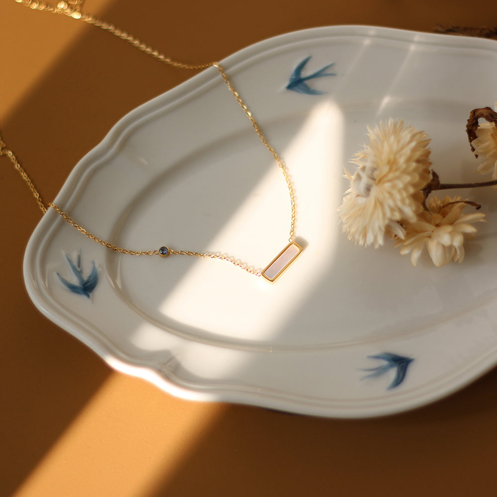 Gold necklace on a decorative plate with dried flowers