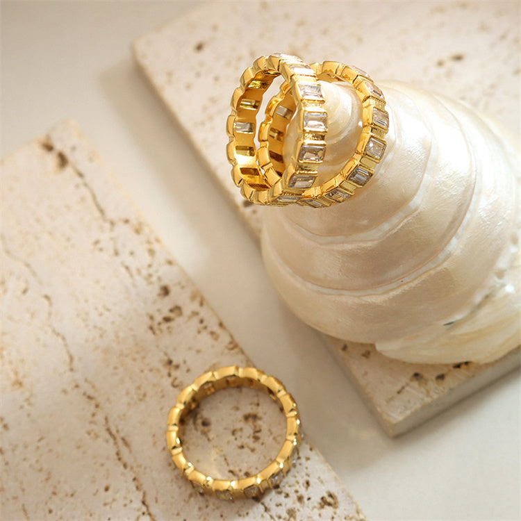 Two gold rings on a textured beige surface