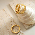 Two gold rings on a textured beige surface