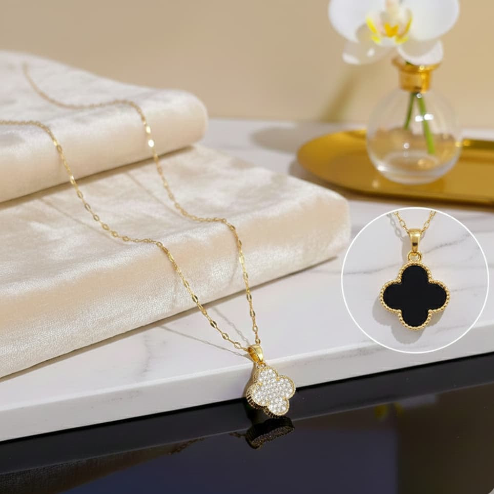Gold necklace with clover-shaped pendant on a marble surface