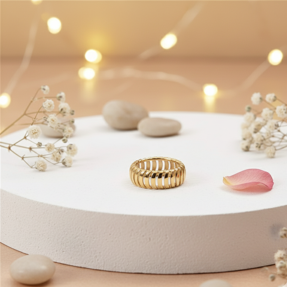 Gold ring on a white platform with decorative elements on a softly blurred background