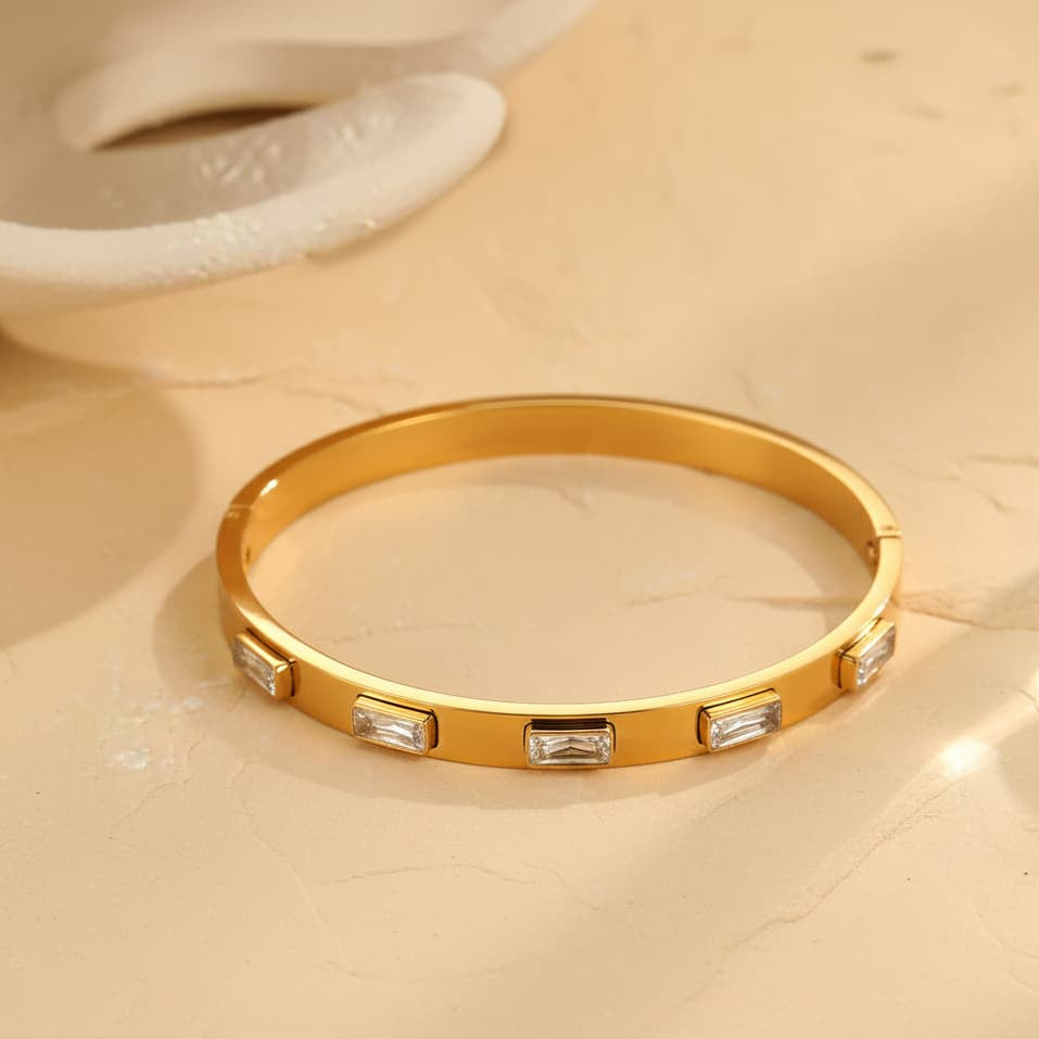 Gold bracelet with gemstones on a beige surface