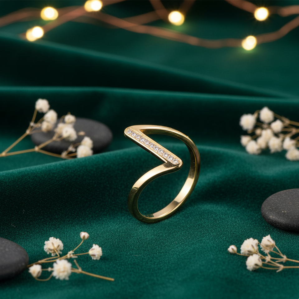 Gold ring on a green fabric background with small white flowers and string lights.
