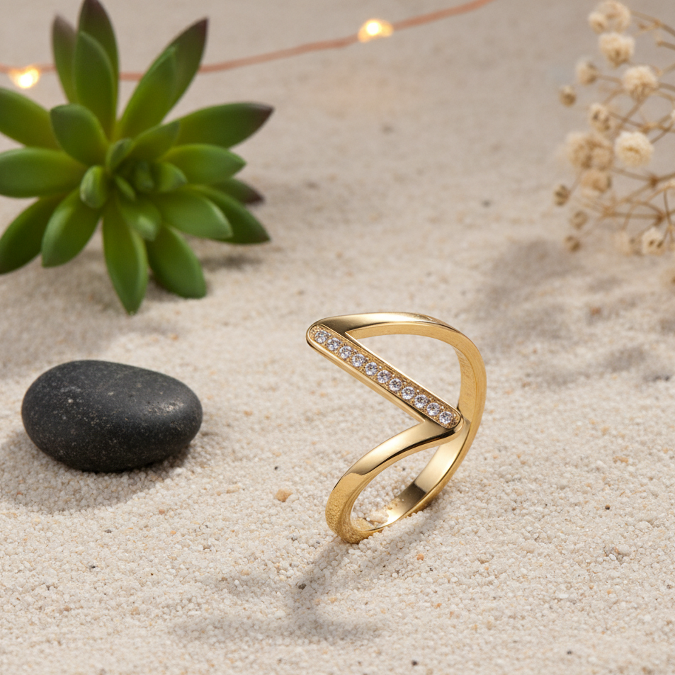 Gold ring with diamond accents on a sandy surface with a stone and plant in the background