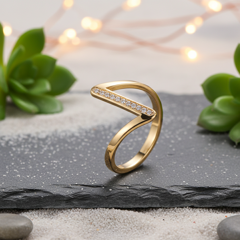Gold ring with embedded stones on a black slate surface with plants and lights in the background