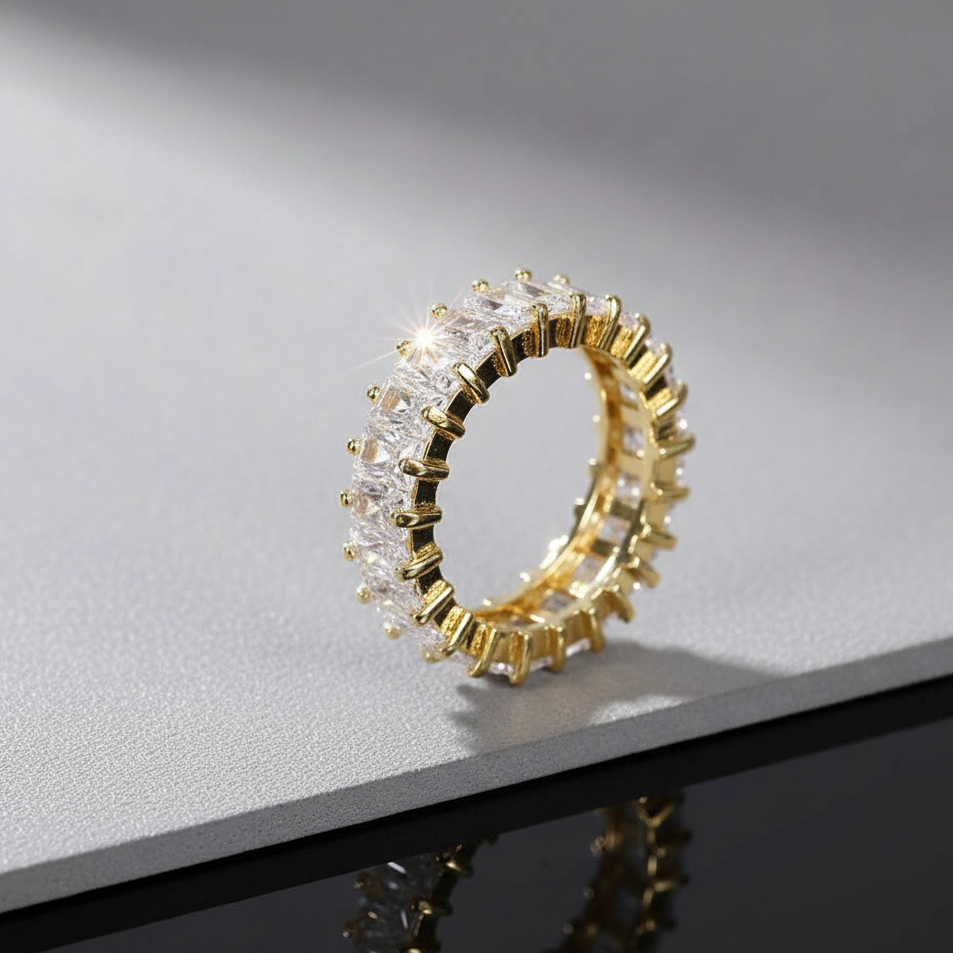 Gold ring with clear gemstones on a reflective surface