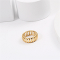 Gold ring on a white surface with a white mug in the background