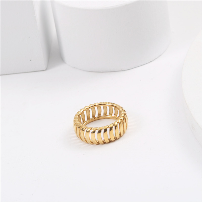 Gold ring on a white surface with a white mug in the background