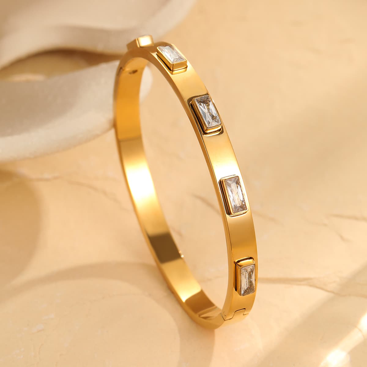 Gold bracelet with embedded stones on a beige background